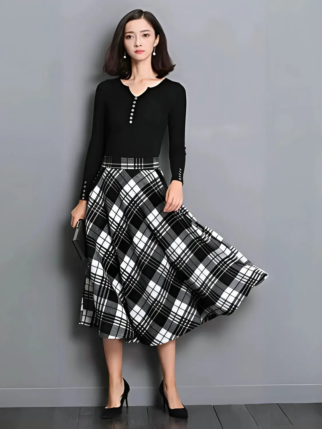 Woman wearing a black top and plaid skirt against a gray background