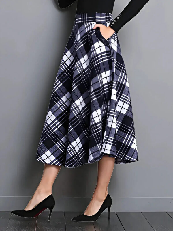 Person wearing a plaid skirt with a black top against a gray background